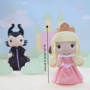 May include: Handmade felt dolls of a princess in a pink dress and a villain in a black cloak. The princess doll is about 14 inches (35 cm) tall. The background features a castle and clouds.