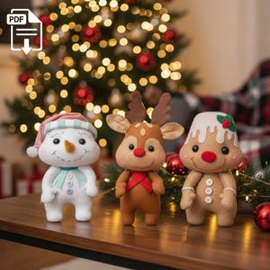 May include: Three festive plush decorations: a snowman, a reindeer, and a gingerbread person. The snowman has a blue scarf and a hat. The reindeer has antlers and a red bow. The gingerbread person has white icing and holly berries.