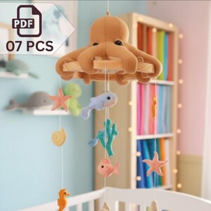 May include: A handmade baby mobile featuring an octopus, starfish, fish, and other sea creatures. The mobile is suspended from a wooden frame and includes the text "07 PCS" in the upper left corner. The mobile is designed to hang over a crib.