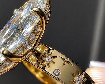 May include: A gold ring featuring a large marquise-cut centre stone held by prongs. The band is engraved with star motifs, each centred with a small round gemstone. Additional small stones are set along the gallery beneath the main stone.