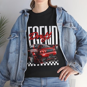 Könnte beinhalten: Schwarzes T-Shirt mit einer roten Sportwagen-Grafik und dem Wort "Drift". Das Design beinhaltet ein Schachbrettmuster am unteren Rand. Das T-Shirt wird mit einer Jeansjacke getragen.