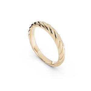 May include: A polished gold ring featuring a continuous twisted rope texture along the outer band. The metal has a reflective, smooth finish with diagonal ridges that create a repeating pattern around the entire circumference of the circular ring.
