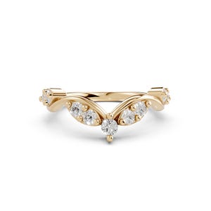 May include: A gold-colored ring with a curved design, featuring multiple small, clear gemstones. The ring's band has a delicate, flowing shape, with the gemstones set in a symmetrical pattern. The ring is likely made of gold.