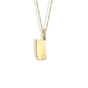 May include: A gold-colored pendant necklace featuring a cleaver design. The cleaver has a polished finish and a small hole near the bottom. The top of the cleaver is adorned with small, clear gemstones. The necklace chain is also gold-colored.
