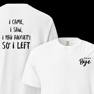 May include: Two white t-shirts. One shirt has the text "I CAME, I SAW, I HAD ANXIETY SO I LEFT" on the back. The other shirt has the text "OKAY Bye" on the front.