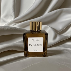 May include: A square, brown glass perfume bottle with a gold cap. The label reads "Svetlo" with a heart symbol, and "Myrrh & Tonka" below. The bottle contains 100ml of fragrance.
