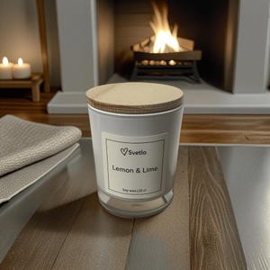 May include: A white glass candle with a wooden lid, labelled "Lemon & Lime" by Svetlo. The candle is on a wooden surface, with a fireplace and lit candles in the background. The candle contains 20 cl of soy wax.