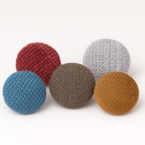 May include: Five round, fabric-covered buttons in blue, red, brown, grey, and gold. The buttons have a textured, knitted appearance against a white background. These buttons are suitable for sewing and craft projects, and are approximately 3 cm in diameter.