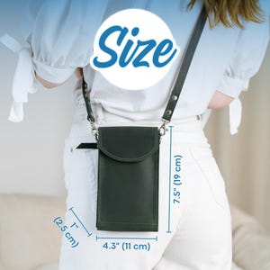 May include: A dark green leather crossbody phone bag with a flap closure and adjustable strap. The bag is 4.3 inches (11 cm) wide, 7.5 inches (19 cm) tall, and 1 inch (2.5 cm) thick. The word "Size" is in a blue circle.