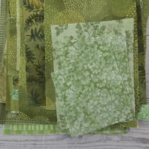 Puede incluir: Una pila de retazos de tela rectangulares en varios tonos de verde. La colecci&oacute;n presenta diversos patrones, incluyendo estampados de hojas bot&aacute;nicas, motivos florales peque&ntilde;os, puntos geom&eacute;tricos y dise&ntilde;os a cuadros, apilados.