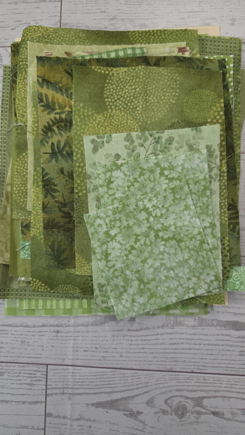 Puede incluir: Una pila de retazos de tela rectangulares en varios tonos de verde. La colecci&oacute;n presenta diversos patrones, incluyendo estampados de hojas bot&aacute;nicas, motivos florales peque&ntilde;os, puntos geom&eacute;tricos y dise&ntilde;os a cuadros, apilados.