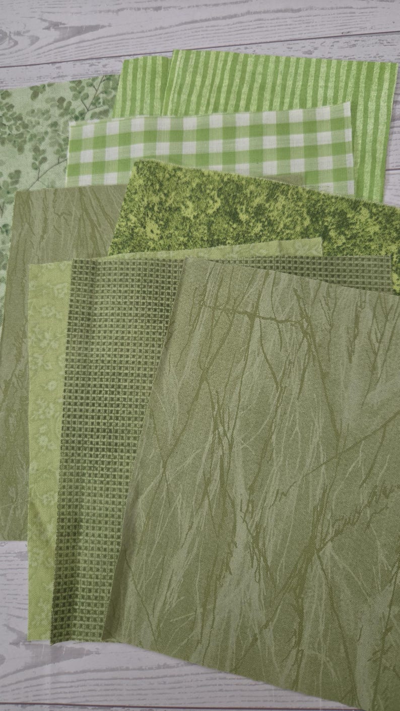 Puede incluir: Una colecci&oacute;n de muestras de tela cuadradas en varios tonos de verde, con diversos patrones que incluyen rayas, cuadros vichy, texturas moteadas, peque&ntilde;os estampados florales, dise&ntilde;os de cuadr&iacute;cula y un sutil motivo de ramas superpuestos.
