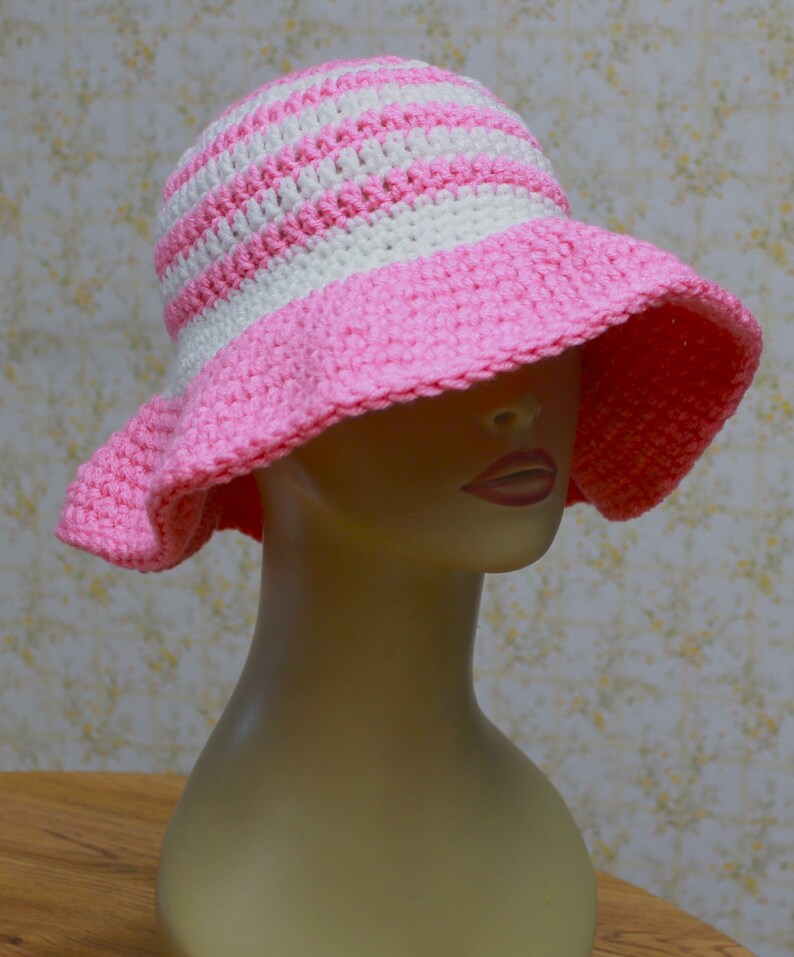 May include: A pink and white striped crochet sun hat with a wide brim.