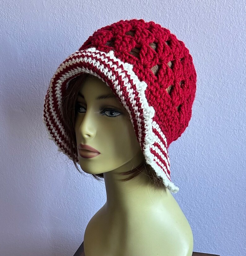 May include: A red and white crocheted hat with a wide brim. The hat has a scalloped edge and a delicate crocheted design.