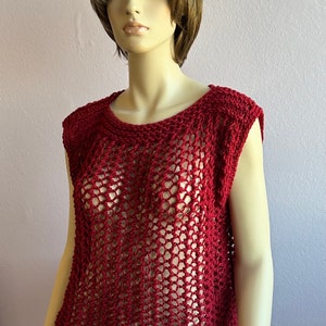 May include: A red crochet top with a loose, open-weave design. The top has a round neckline and sleeveless design.