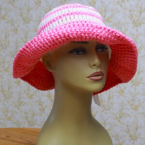 May include: A pink and white striped crochet sun hat with a wide brim.