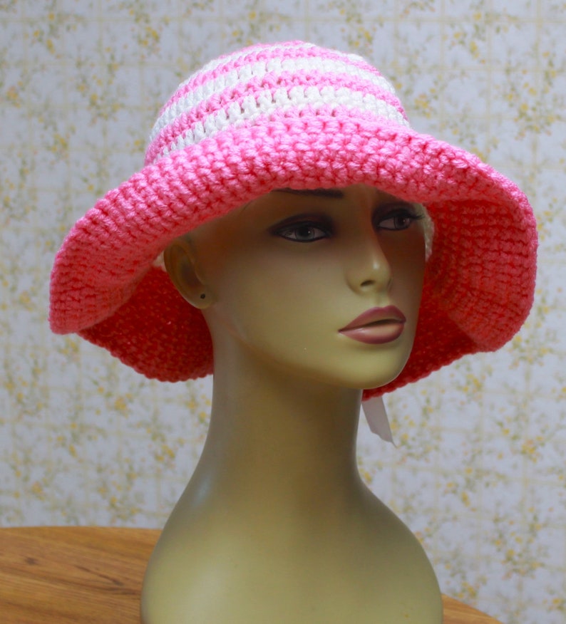 May include: A pink and white striped crochet sun hat with a wide brim.