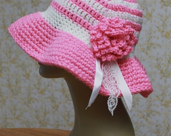 May include: A pink and white striped crochet sun hat with a pink crocheted flower and a white lace trim.