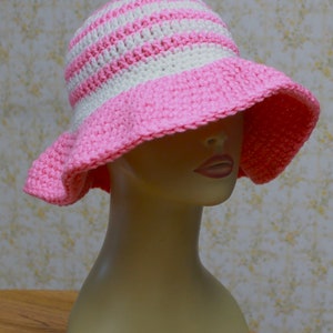 May include: A pink and white striped crochet sun hat with a wide brim.