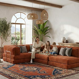 以下が含まれることがあります： 大きなモジュール式の錆色のコーデュロイソファがある居心地の良いリビングルーム。模様入りのラグと装飾的なクッションが暖かさを添えています。女性と2人の子供がソファに座り、本と玩具を持っています。大きな窓から自然光が差し込んでいます。