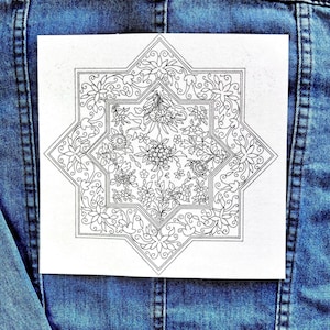 May include: A white, eight-pointed star-shaped patch with a detailed floral design in black. The patch features various flowers and leaves, with a border of intricate patterns. The patch is placed on a blue denim jacket.