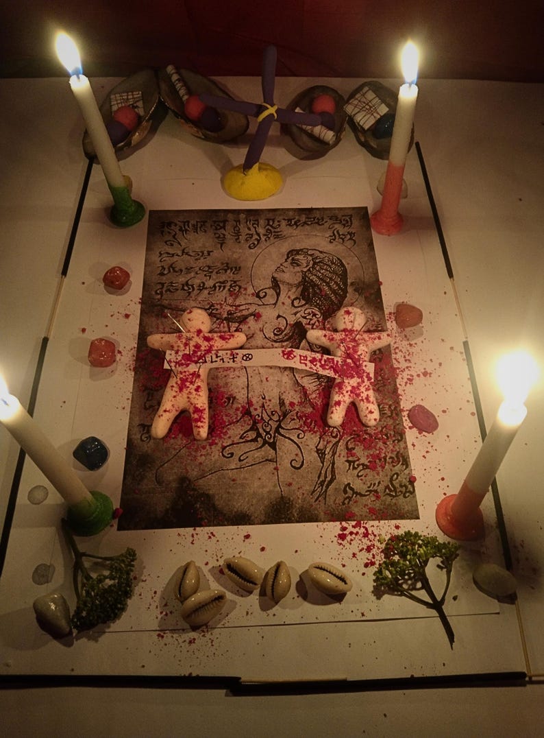 Puede incluir: Una impresi&oacute;n rectangular con una ilustraci&oacute;n central de una figura rodeada de escritura, dos peque&ntilde;as figuras humanoides de color beige con motas rojas, cuatro velas encendidas, conchas de cauri dispersas, piedras de colores y ramitas verdes.