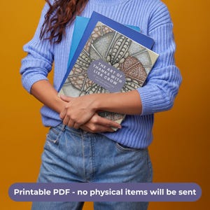 May include: A book titled The Art of Thanks with Lisa Crow, 30 Days of Gratitude and Zentangle, featuring a complex, patterned, monochromatic and tan-toned cover design with a blue rectangular label, held against a solid mustard yellow background.