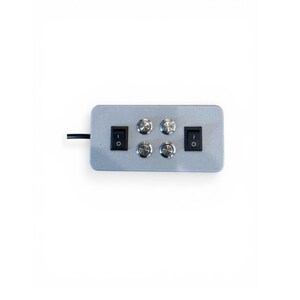 Puede incluir: Un panel de control rectangular plateado con dos interruptores de encendido/apagado negros y cuatro perillas giratorias plateadas. Un cable negro se extiende desde el lado izquierdo. El panel est&aacute; sobre un fondo blanco.