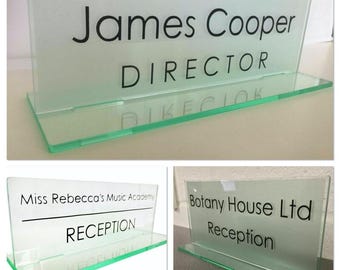 May include: A clear glass desk sign displaying the name "James Cooper" and the title "DIRECTOR" in black. The sign has a frosted finish and a green-tinted edge. Other signs read "Miss Rebecca's Music Academy" and "Botany House Ltd".