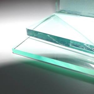 Peut inclure: Gros plan sur deux panneaux de verre rectangulaires aux bords arrondis. Le verre a une légère teinte verte et reflète la lumière, créant des reflets et des ombres. Les panneaux sont empilés, l'un chevauchant partiellement l'autre.
