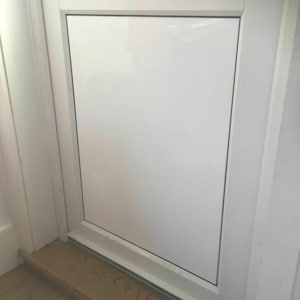 May include: A white, glossy door set within a white frame. The door is rectangular and closed. The image shows a section of the door frame, the door itself, and a portion of the wooden floor. The floor is made of wood.