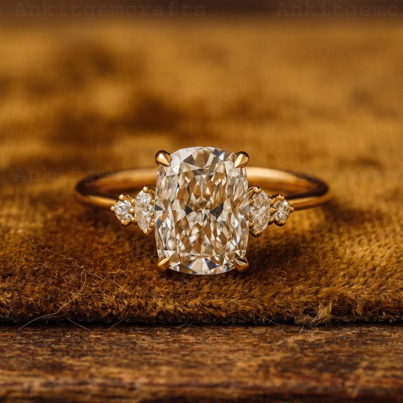 May include: A gold ring featuring a large, rectangular-cut diamond as the centerpiece, flanked by smaller, pear-shaped diamonds. The ring's band is a simple, polished gold. The overall design is elegant and classic, suitable for engagement or special occasions.