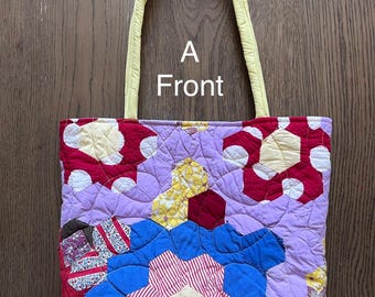 Könnte beinhalten: Eine gesteppte Tragetasche mit einem Patchwork aus sechseckigen Stoffstücken in Rot, Blau, Gelb und Lavendel mit Blumen- und Streifenmustern. Die Tasche hat zwei hellgelbe Stoffgriffe und den in Weiß aufgedruckten Text A Front.