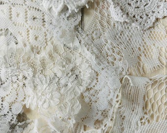 May include: A collection of white lace fabric scraps featuring various textures and patterns, including floral motifs, intricate crochet work, and open-weave netting, layered together to display diverse embroidery styles and delicate threadwork.