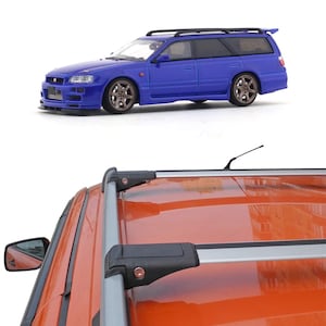 May include: A blue model car with a spoiler and brown wheels is shown from a side view. The car has a black roof rack. The bottom of the image shows a close-up of an orange car roof with a silver roof rack.