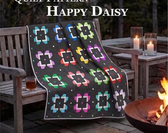 May include: A dark gray quilt featuring a repeating pattern of colorful daisy-like shapes in blue, purple, red, yellow, and green. The text reads Quilt Pattern Happy Daisy and Quilt Size: 78 inches x 78 inches. The quilt is draped over a wooden bench.