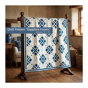 Könnte beinhalten: Eine cremefarbene Steppdecke mit einem geometrischen blauen Muster, die auf einem Holzgestell präsentiert wird. Die Steppdecke weist ein sich wiederholendes Design aus Diamanten und Kreuzen auf. Der Text auf dem Bild lautet "Quilt Pattern 'Sapphire Facets'" und "Quilt Size: 190cm x 190cm"
