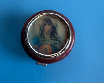 Una caja redonda de madera con una imagen lenticular de Jesús y María.
