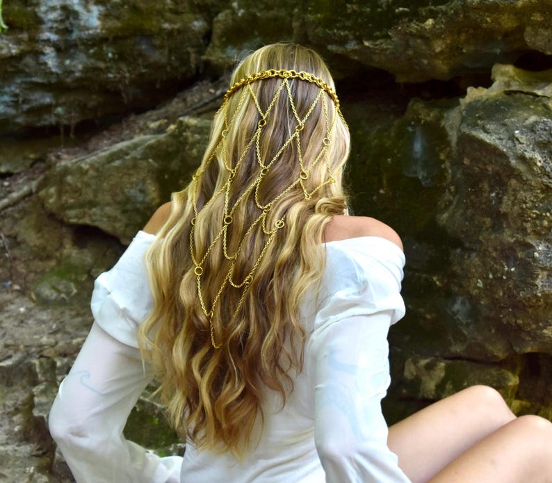 May include: A gold-toned metal chain headpiece featuring a delicate, interconnected net design that drapes over the back of the head. The accessory is constructed from thin, polished links and small circular rings, creating a cascading, layered effect.