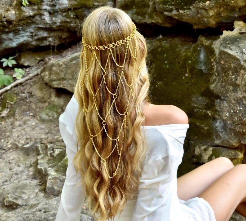 May include: A gold-toned hair accessory featuring a delicate chain headpiece that drapes over the back of the head. The design consists of a circular link headband connected to a cascading net of fine gold chains that hang down the hair.