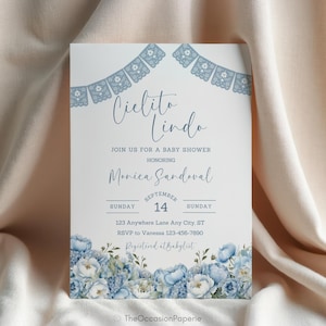 Könnte beinhalten: Eine Babyparty-Einladung mit den Worten "Cielito Lindo" in eleganter Schrift. Die Einladung zeigt blaue florale Akzente und dekorative Banner. Der Text enthält den Namen der Geehrten, Datum, Uhrzeit und RSVP-Informationen.