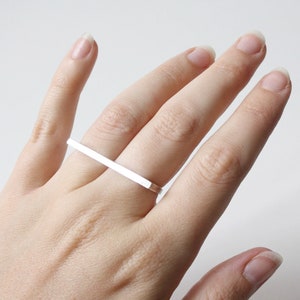May include: A silver ring with a long, rectangular bar that spans two fingers.