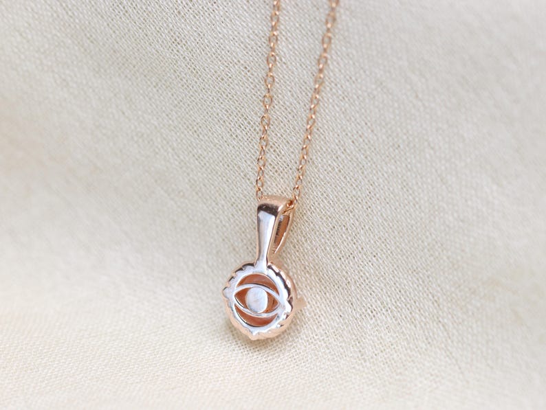 May include: A rose gold necklace with a delicate eye pendant. The pendant is detailed with a white stone in the center.