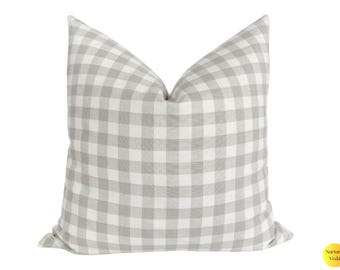 May include: A square decorative pillow with a gray and white gingham pattern. The pillow has a soft, textured appearance and is designed for home decor. The pillow is a neutral color and can be used in a variety of settings.