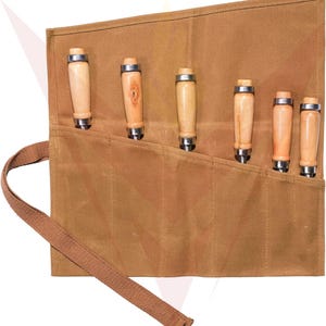 May include: A set of six wood carving tools with light-colored wooden handles and metal ferrules, stored in a brown canvas roll with a matching strap. The tools are arranged in a row, showcasing their sharp blades.