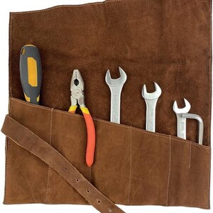 May include: A brown leather tool roll with a variety of tools. The tools include a screwdriver, pliers, and several wrenches. The roll has a strap for securing the tools.