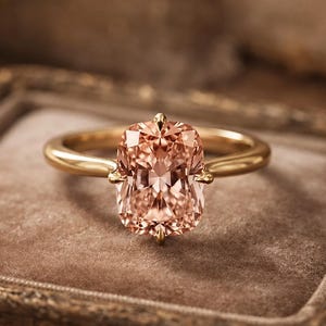Può includere: Un anello in oro con una grande pietra preziosa rettangolare color pesca a taglio cuscino, fissata con quattro griffe. La fascia è liscia e lucida, caratterizzata da una calda lucentezza metallica che completa la tonalità arancio chiaro.