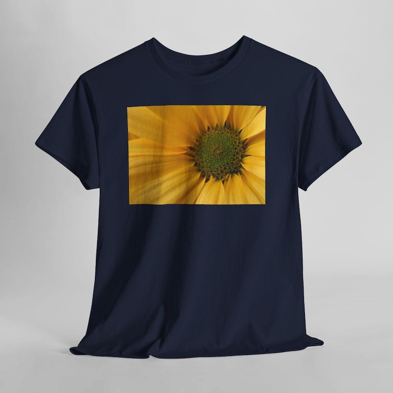 K&ouml;nnte beinhalten: Marineblaues T-Shirt mit einem Nahaufnahme-Bild einer gelben Blume mit gr&uuml;nem Zentrum. Die Bl&uuml;tenbl&auml;tter der Blume sind detailliert, und das T-Shirt besteht aus einem weichen Material. Das Design ist auf dem T-Shirt zentriert.