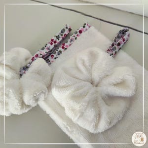 Può includere: Primo piano di un set spa bianco e soffice. Il set include un piccolo asciugamano piegato, due scrunchies e due fermagli per capelli rivestiti in tessuto con un motivo floreale rosa, bianco e verde. Gli oggetti sono disposti su una superficie bianca.