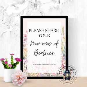 Könnte beinhalten: Ein gerahmtes Schild mit dem Text "PLEASE SHARE YOUR Memories of Beatrice". Das Schild ist mit floralen Elementen und einer kleinen Laterne verziert. Eine Vase mit rosa Blumen und eine einzelne rosa Blume befinden sich im Vordergrund.